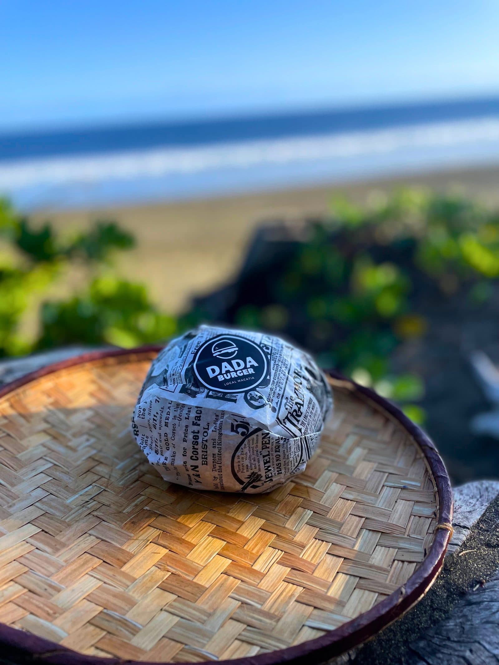 Burger Dada Burger emballé, posé face à l'océan à La Réunion